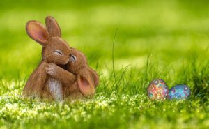 Image of two bunnies huging with easer eggs in the grass.