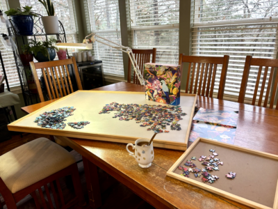 Image of puzzle board with pieces on table with floor light and teacup